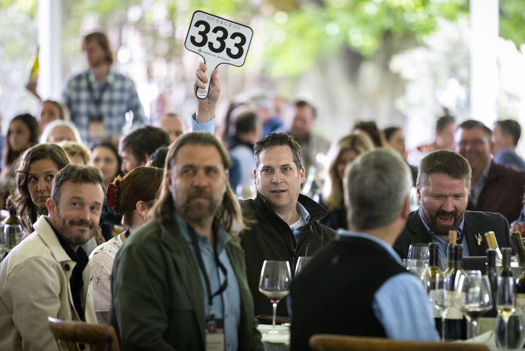 Josh Kirchhoff, with Underground Cellars, raises his paddle to win 10 cases of Limerick Lane Cellars Zinfandel at the Sonoma County Barrel Auction at the MacMurray Ranch on Friday, May 6, 2022.  (John Burgess/The Press Democrat)