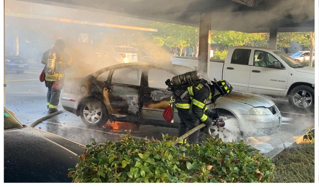 Firefighters try to put out a fire that engulfed a silver Volkswagen Friday at the Harvest Park Apartments in south Santa Rosa. (Tyler Silvey / The Press Democrat)