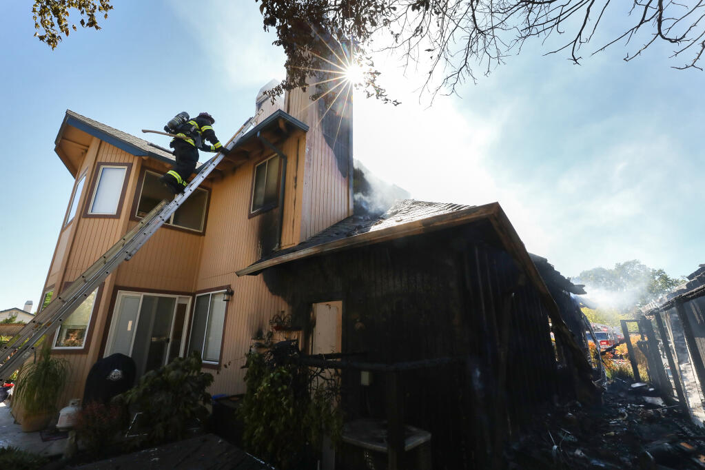Sonoma County Fire District Capt. Fred Leuenberger climbs a ladder onto the roof of a house to vent a chimney on Pistachio Place in Windsor on Tuesday, April 27, 2021. (Christopher Chung / The Press Democrat)