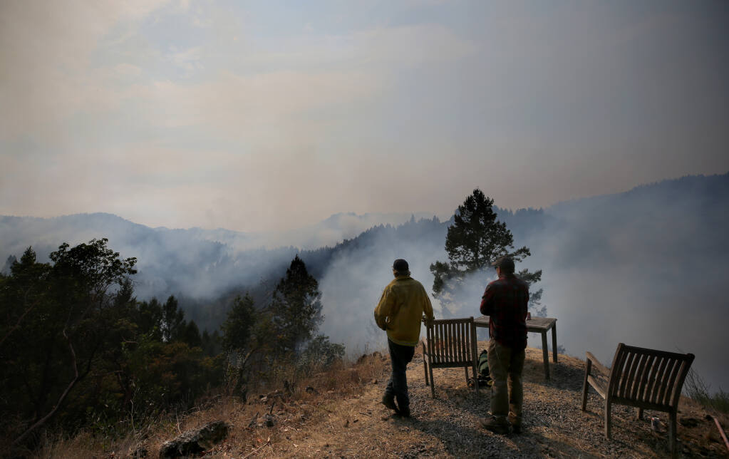 Members of the Peterson family look out from their Sweetwater Springs Road property towards Armstrong Redwoods State Natural Reserve as smoke from the Walbridge fire rises above the trees in Guerneville, Calif., on Sunday, Aug. 23, 2020. (BETH SCHLANKER/ The Press Democrat)