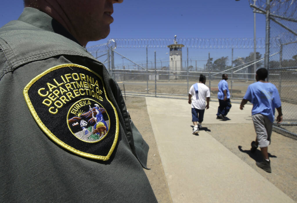 FILE - In this June 20, 2018 file photo, inmates pass a correctional officer as they leave an exercise yard at the California Medical Facility in Vacaville, Calif. (AP Photo/Rich Pedroncelli, File)