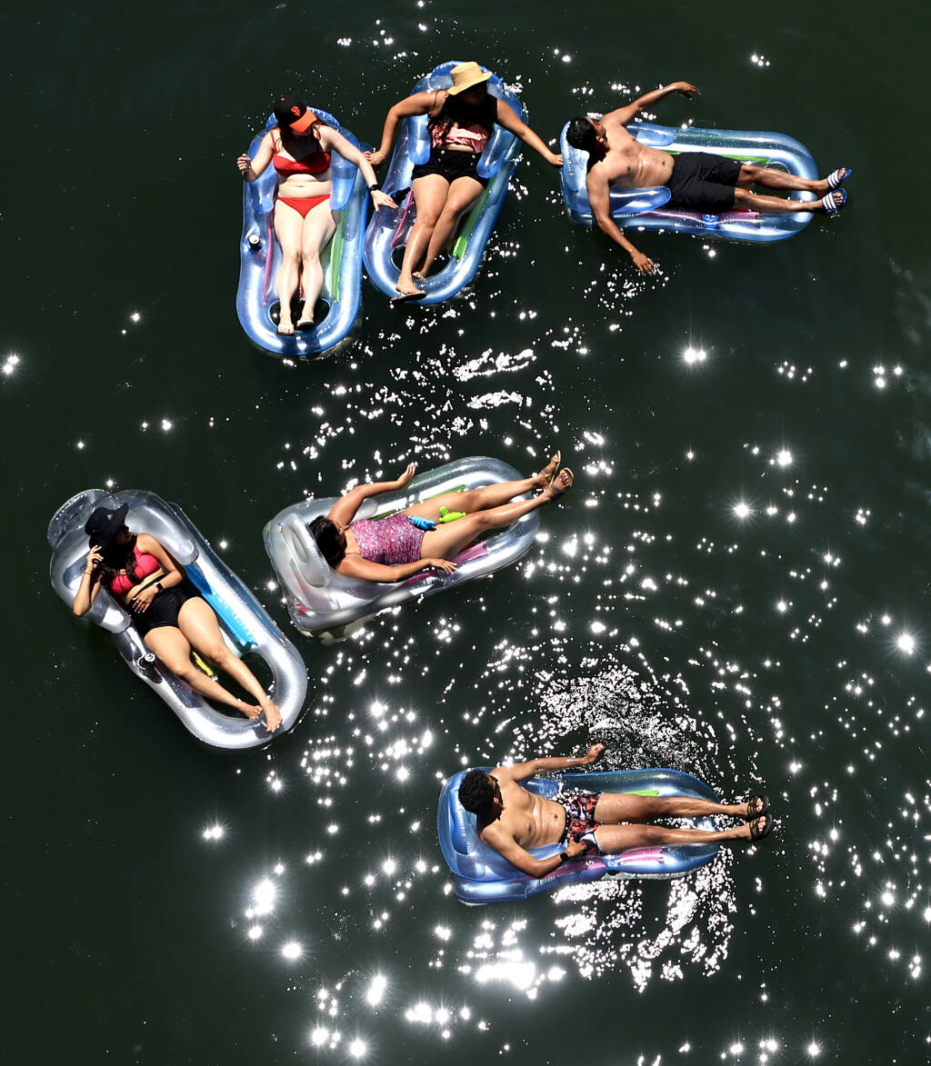 A group of adults float down the Russian River in Monte Rio, Saturday, June 12, 2021.  (Kent Porter / The Press Democrat) 2021