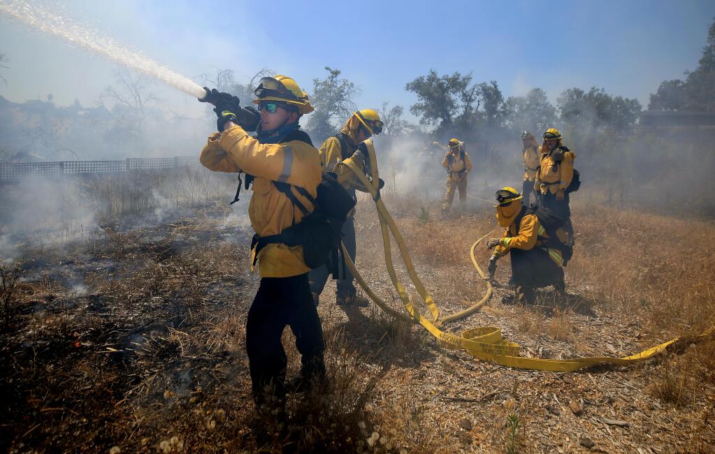 Joel Ferguson of the Sonoma County Fire District and Cal Fire personal complete a progressive hose lay to stop the forward spread of a 1.6 acre brush fire in the old Tubbs fire burn scar along Mark West Springs Road, Friday, June 26, 2020. (Kent Porter / The Press Democrat) 2020