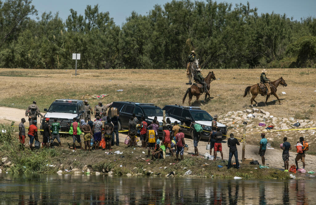 FILE - U.S. border patrol officers contain a group of migrants on the shore of the Rio Grande after they crossed from Ciudad Acuña, Mexico, into Del Rio, Texas, Sept. 19, 2021. Border Patrol agents on horseback engaged in "unnecessary use of force" against non-threatening Haitian immigrants but didn't whip any with their reins, according to a federal investigation of chaotic scenes along the Texas-Mexico border last fall. (AP Photo/Felix Marquez, File)