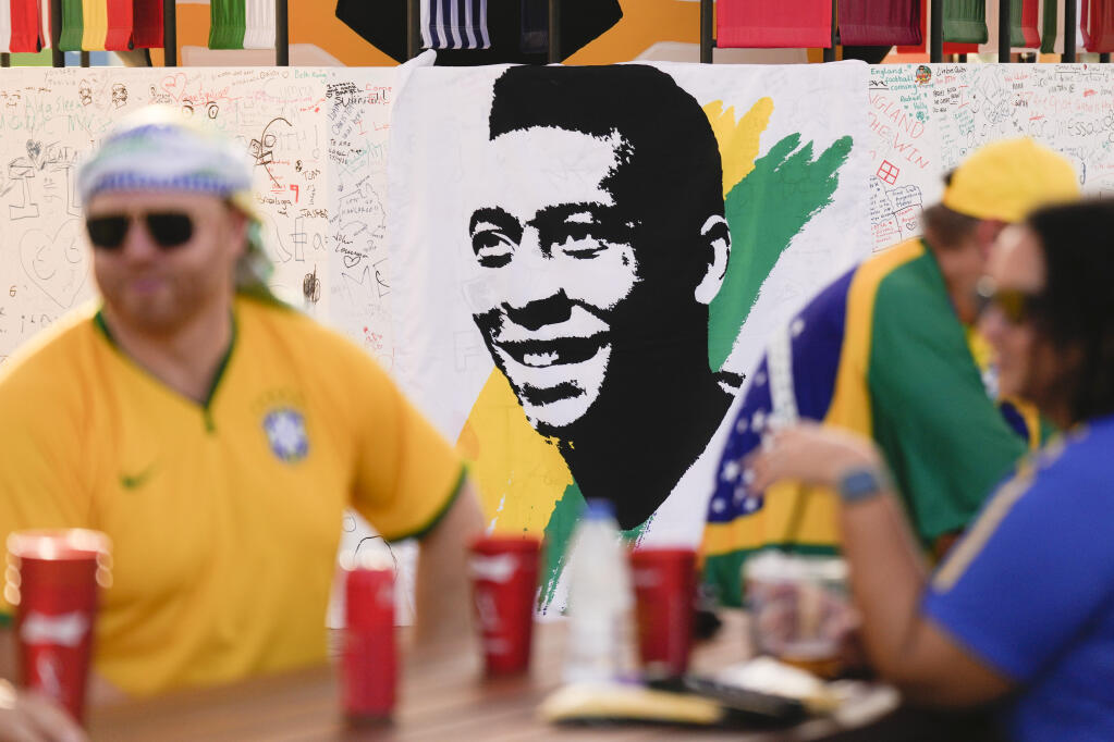 A portrait of Pelé is displayed at a Brazilian fan party before the the World Cup round of 16 soccer match between Brazil and South Korea, in Doha, Dec. 5, 2022. The 82-year-old Pelé remained in a hospital in San Paulo recovering from a respiratory infection that was aggravated by COVID-19, but the news coming from Brazil early Monday was good. (AP Photo/Ashley Landis)