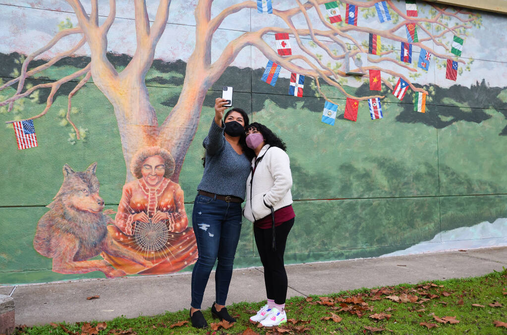 Former Elsie Allen Spanish teacher Angelica Salas de Torres, left, and youth organizer Raquel Guevara take a photo together at the unveiling of the “Weaving Cultures” mural at Elsie Allen High School in Santa Rosa on Monday, November 15, 2021. (Christopher Chung/ The Press Democrat)