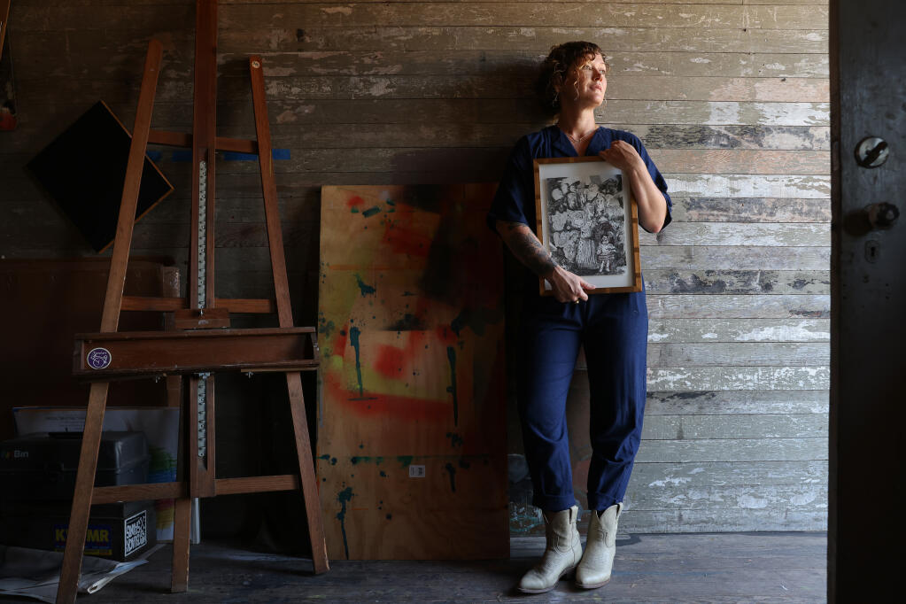Artist Beth Tisthammer holds a piece by her friend, the late artist Hamlet Mateo, from his Early Man comic in her studio in Petaluma, California, on Tuesday, Sept. 6, 2022. Mateo gave it to her as a wedding present. (Christopher Chung/The Press Democrat)