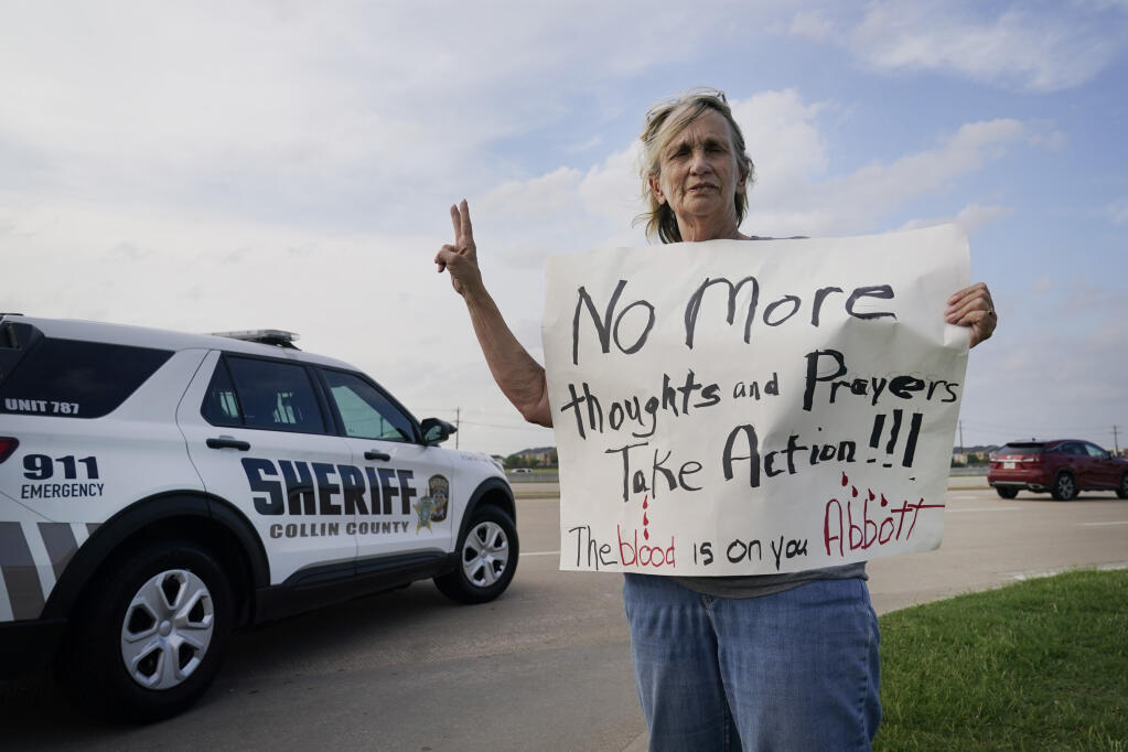 Mary Ann Foley holds a protest sign outside a prayer vigil following a mass shooting the day before, Sunday, May 7, 2023, in Allen, Texas. (AP Photo/LM Otero)