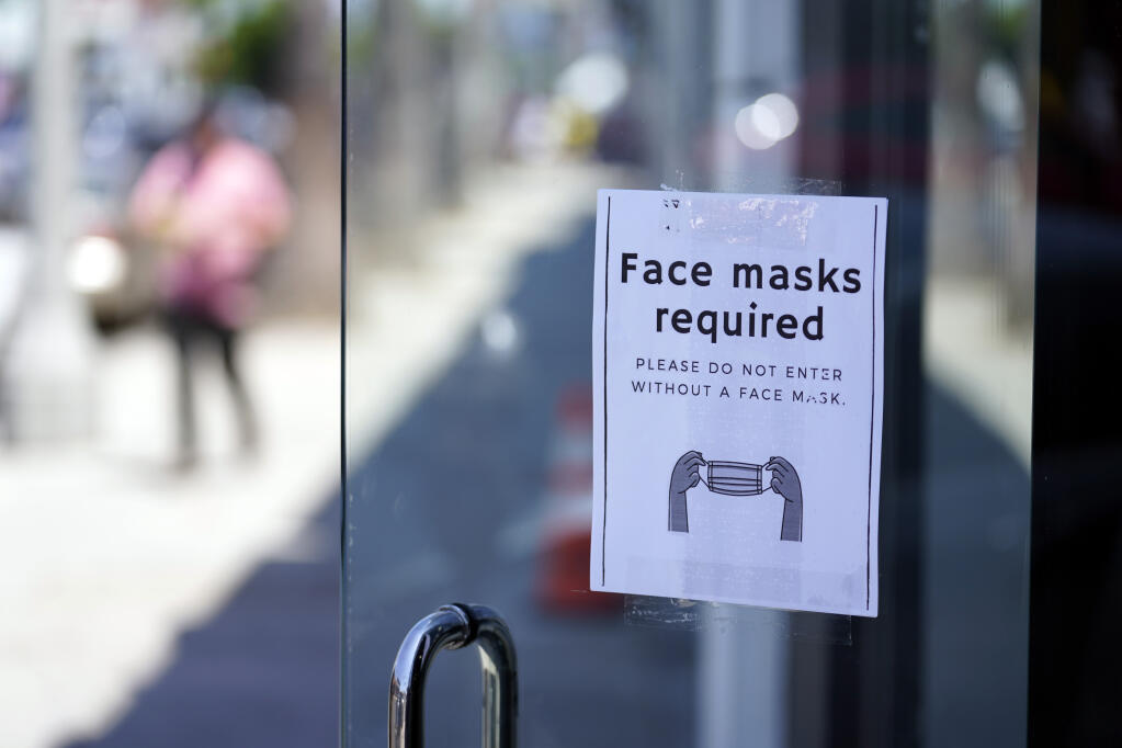 FILE - A sign advises shoppers to wear masks outside of a story Monday, July 19, 2021, in the Fairfax district of Los Angeles. (AP Photo/Marcio Jose Sanchez)