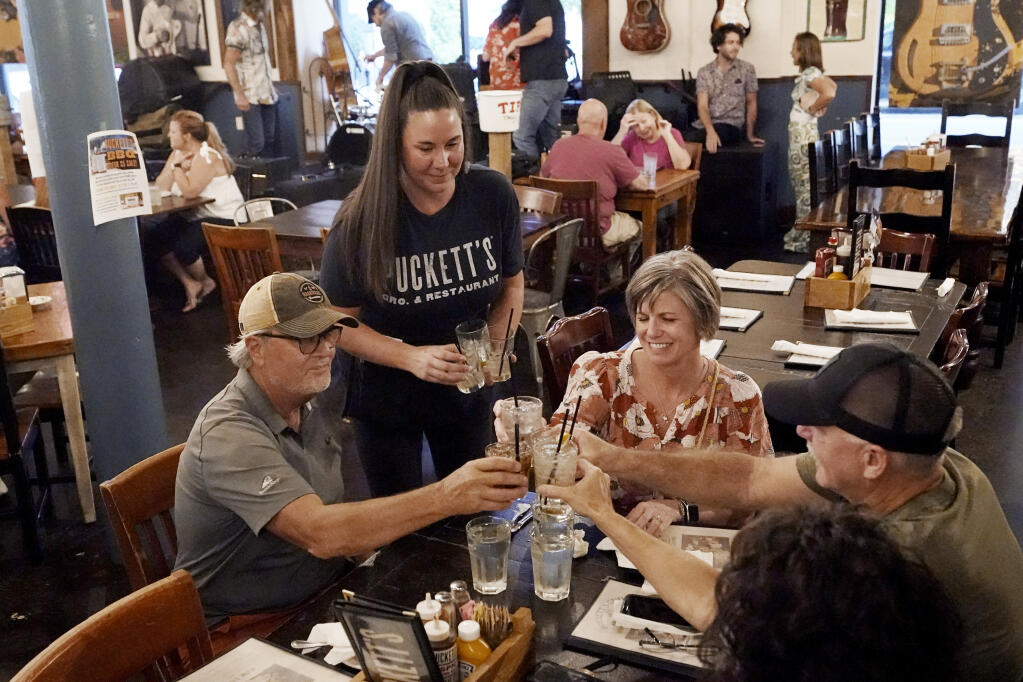 Macy Norman, center, serves a table of guests at Puckett's Grocery and Restaurant, Friday, Sept. 10, 2021, in Nashville, Tenn. Nearly 12,000 people left California for Tennessee in 2019, according to U.S. Census Bureau data, up from roughly 9,600 in 2018 and about 7,900 in 2017. (AP Photo/Mark Humphrey)
