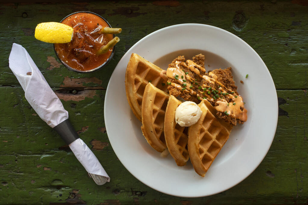 Chicken & Waffles comes with sriracha cream and organic maple butter, served here with a Bloody Mary, at Gypsy Cafe in Sebastopol. (John Burgess / The Press Democrat)
