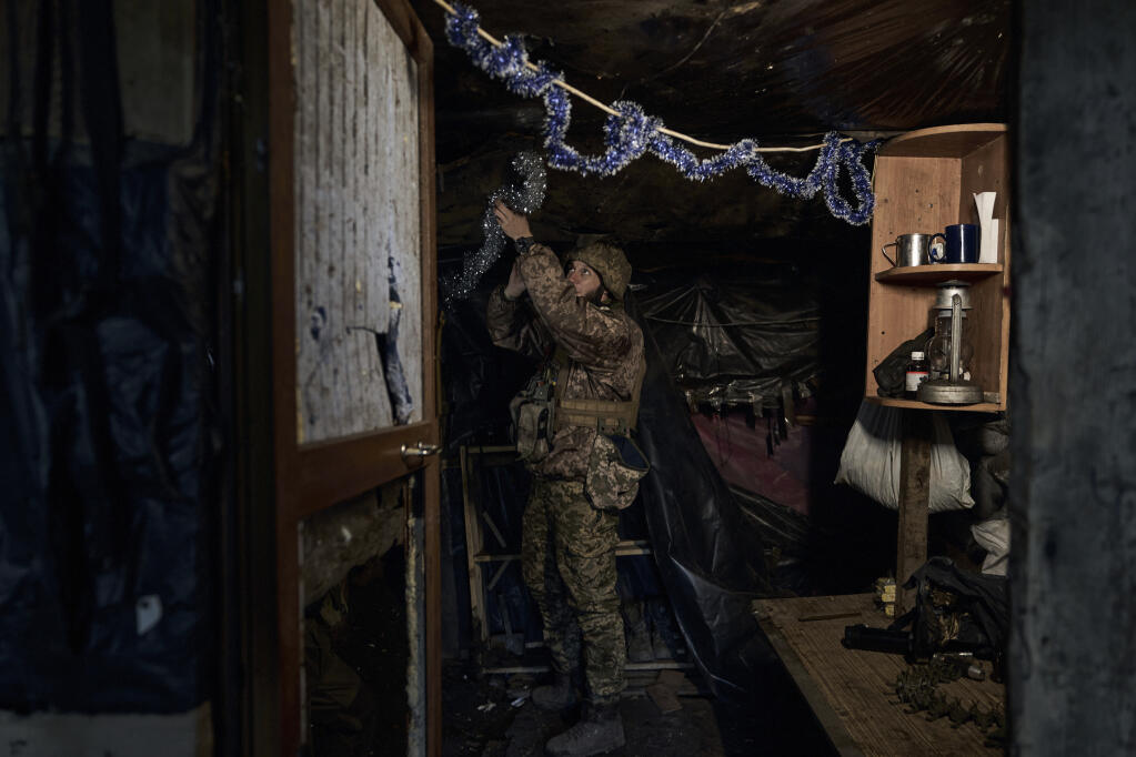 A Ukrainian soldier decorates a frontline position during fights with Russian forces near Maryinka, Donetsk region, Ukraine, Friday, Dec. 23, 2022. (AP Photo/Libkos)