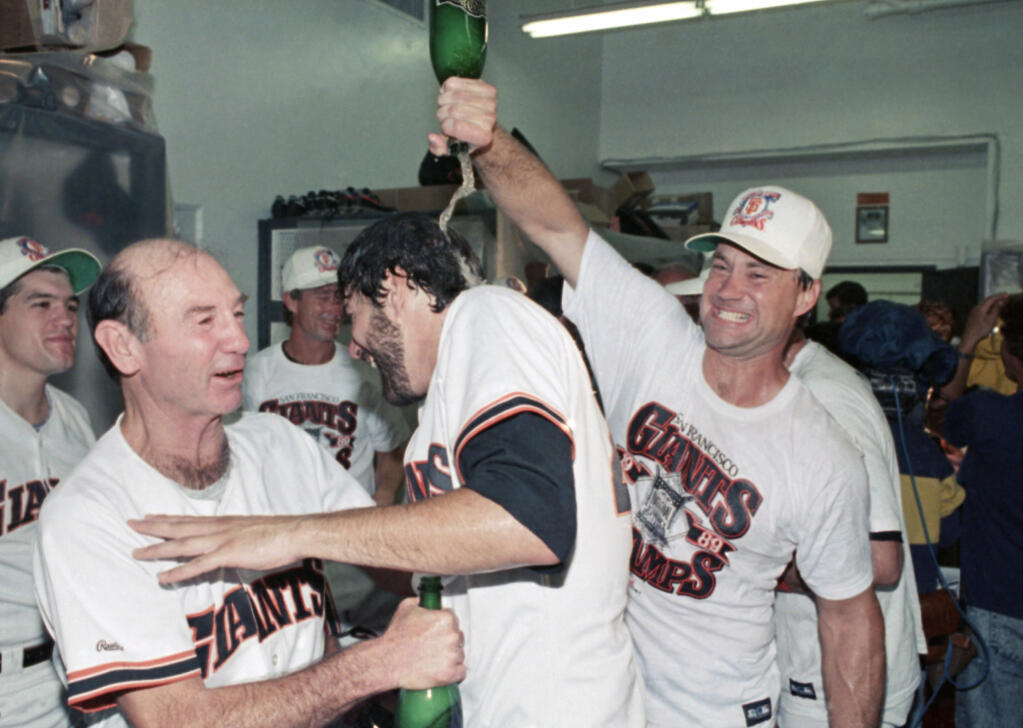 FILE - In this Oct. 9, 1989, file photo, San Francisco Giants catcher Terry Kennedy, right, pours sparkling wine over the head of Steve Bedrosian, center, as pitching coach Norm Sherry watches at left following the Giants' victory over the Chicago Cubs to secure the National League pennant in San Francisco. Sherry, whose suggestion to Los Angeles Dodgers teammate Sandy Koufax helped cultivate the future Hall of Fame pitcher's potential, has died. He was 89. Sherry died Monday, March 8, 2021, of natural causes at an assisted living facility in San Juan Capistrano, Calif., his son Mike told The Associated Press on Wednesday. (AP Photo/Eric Risberg, File)