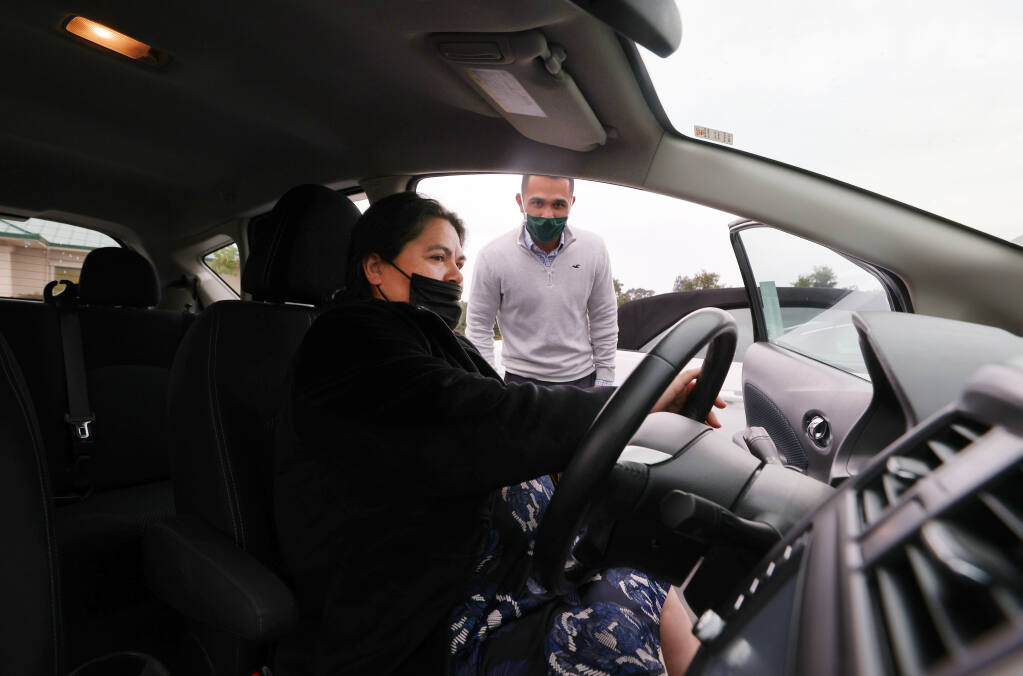 Sales adviser Carlos Ruvalcaba shows a vehicle to Susana Lua at RCU Auto Services in Santa Rosa on Thursday, Nov. 18, 2021. (Christopher Chung/ The Press Democrat)