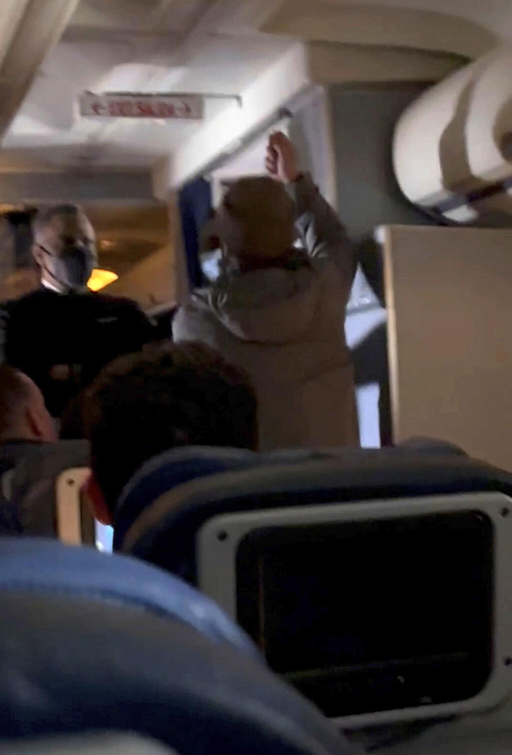 In this still image from video provided by Lisa Olsen, a man, who federal authorities have identified as Francisco Severo Torres, raises his hand before attacking a flight attendant in the cabin of a weekend flight from Los Angeles to Boston, Sunday, March 5, 2023. Federal authorities said Torres tried to open the airliner's emergency exit and then tried to stab a flight attendant with a broken spoon. (Lisa Olsen via AP)