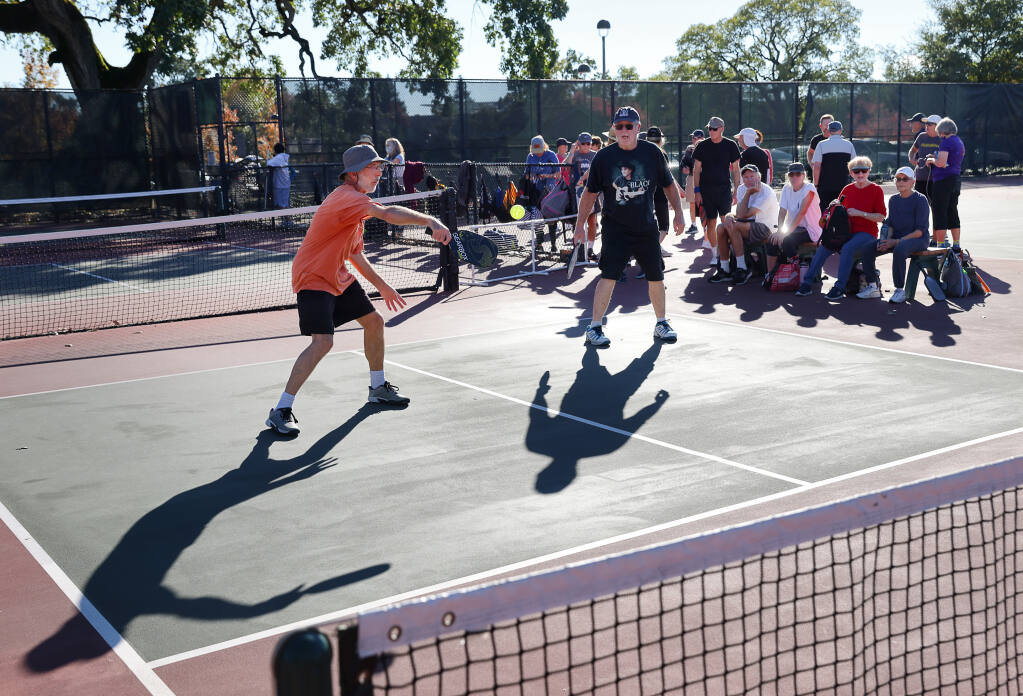 Two Alexander, left, and Norm McGaffey play a game of pickleball as fellow players gather to their numbers at Finley Community Park in Santa Rosa on Wednesday, October 27, 2021.  (Christopher Chung/ The Press Democrat)
