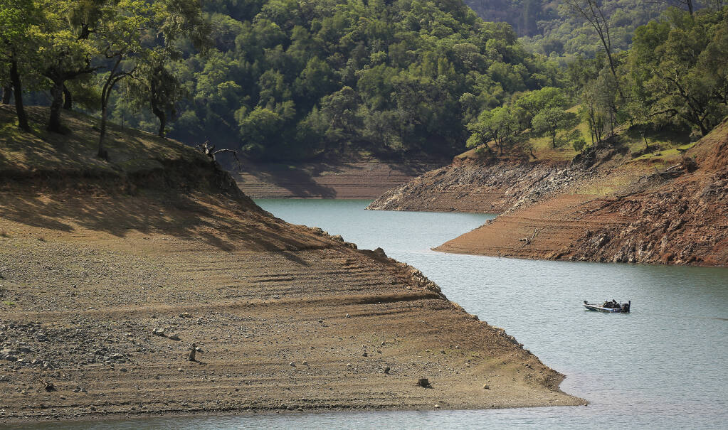 A boater navigates Lake Sonoma and its ever increasing steep shoreline, Friday, April 2, 2021,  200 yards west of the private marina. The lake is at 63.09% of capacity, the lowest point in history for this time of year.  (Kent Porter / The Press Democrat)