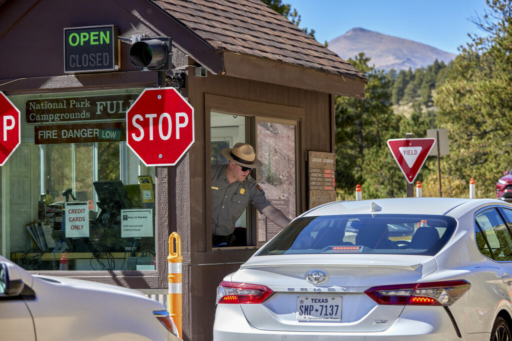 FILE — A park ranger greets visitors by collecting entrance fees at the Fall River entrance to Rocky Mountain National Park in Colo., on Sept. 21, 2023. The National Park Service is continuing to convert dozens of its sites across the country to cashless payments only, drawing complaints and, now, a lawsuit. (Stephen Speranza /The New York Times)