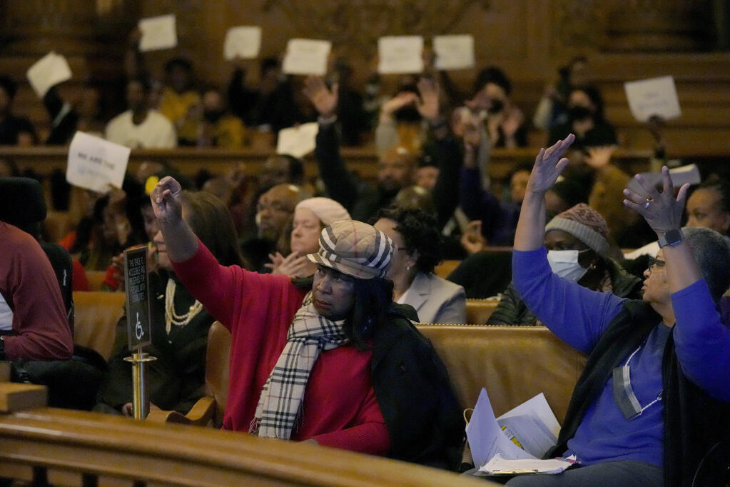 People react to speakers during a special Board of Supervisors hearing about reparations in San Francisco, Tuesday, March 14, 2023. Supervisors in San Francisco are taking up a draft reparations proposal that includes a $5 million lump-sum payment for every eligible Black person. (AP Photo/Jeff Chiu)