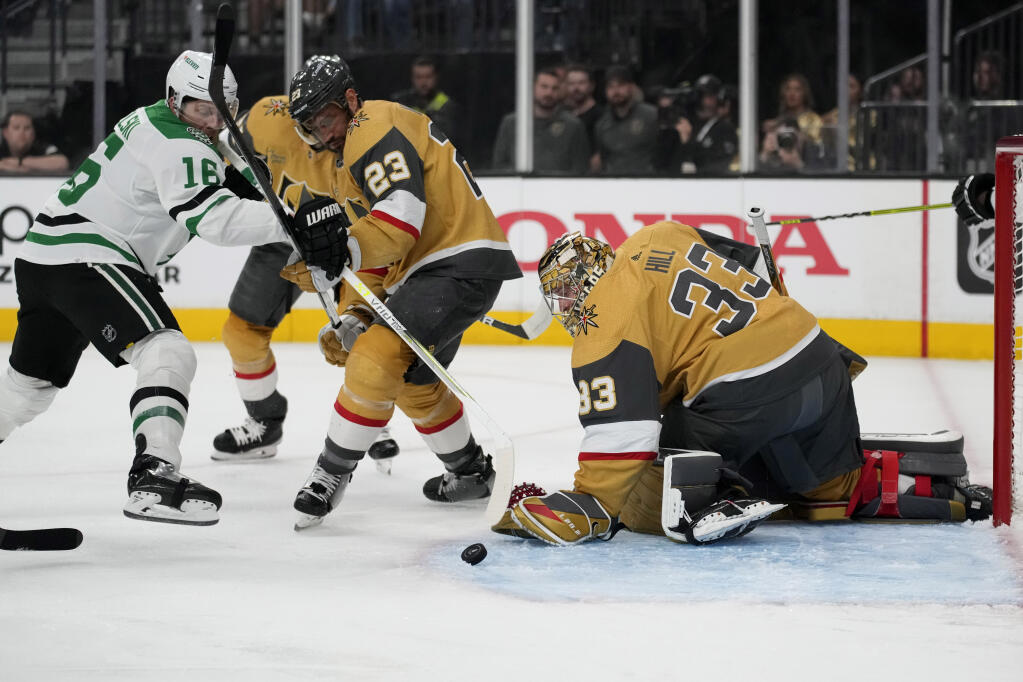 Vegas Golden Knights goaltender Adin Hill (33) stops the puck beside Dallas Stars center Joe Pavelski (16) AND Vegas Golden Knights defenseman Alec Martinez (23) during the first period of Game 5 of the NHL hockey Stanley Cup Western Conference finals Saturday, May 27, 2023, in Las Vegas. (AP Photo/John Locher)