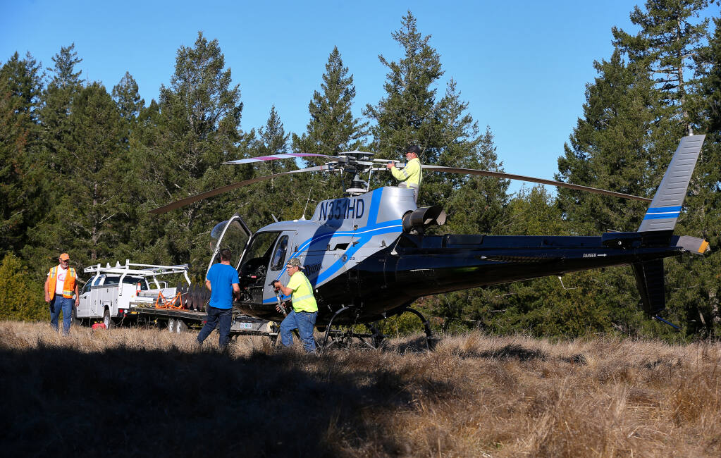 A Heli-Dunn crew refuels one of the company’s Heli-Saws at a landing zone near Tin Barn Road in northwest Sonoma County before returning to trim trees along PG&E transmission lines on Tuesday, Dec. 8, 2020. (Christopher Chung / The Press Democrat)