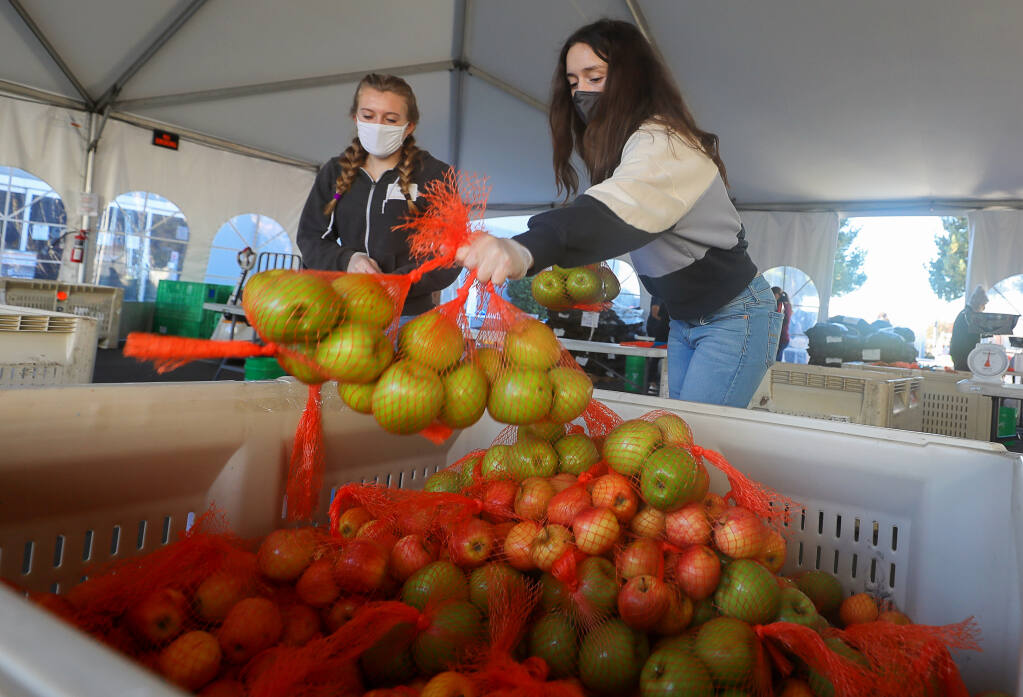 Alex Barnes, right, and Capri Reed pack bags of apples at Redwood Empire Food Bank, north of Santa Rosa on Monday, Nov. 23, 2020. (Christopher Chung / The Press Democrat)