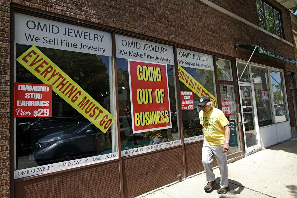A man walks past a retail store that is going out of business due to the coronavirus pandemic in Winnetka, Ill., Tuesday, June 23, 2020. Illinois Gov. J.B Pritzker announced a package of state grant programs that will help support communities and businesses impacted by the COVID-19 pandemic and unrest in the area. (AP Photo/Nam Y. Huh)