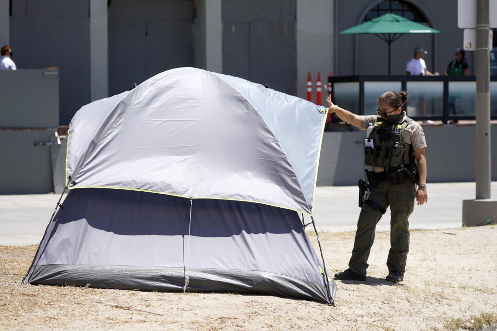 A member of Los Angeles County Sheriffs Department's HOST, Homeless Outreach Service Team, talks to a homeless person Tuesday, June 8, 2021, in the Venice Beach section of Los Angeles. (AP Photo/Marcio Jose Sanchez)