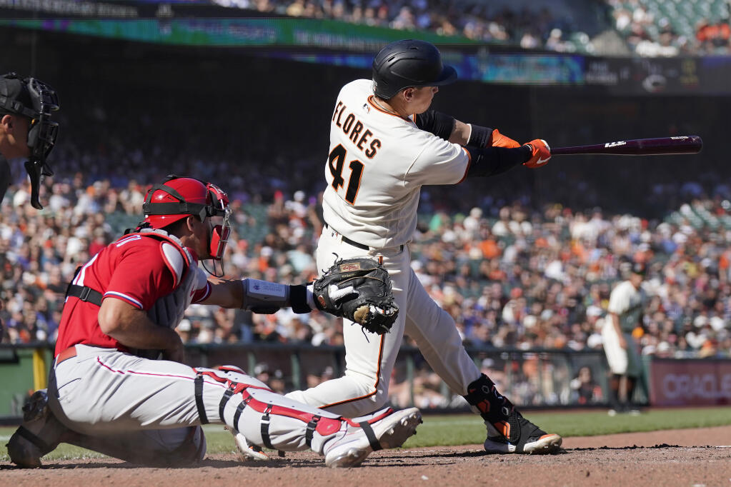San Francisco Giants' Wilmer Flores (41) hits a two-run home run in front of Philadelphia Phillies catcher J.T. Realmuto during the ninth inning of a baseball game in San Francisco, Sunday, Sept. 4, 2022. (AP Photo/Jeff Chiu)