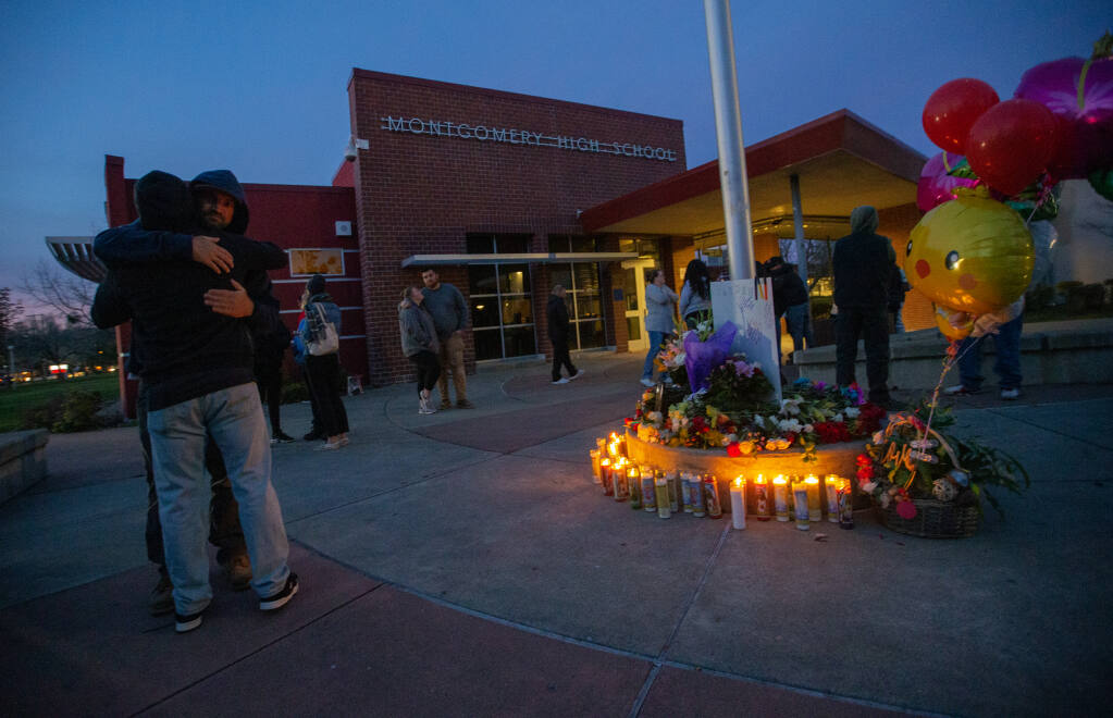 Mourners hug near a candlelight memorial at the entrance to Montgomery High School after a student fight resulted in the death of a 16-year-old student, Wednesday,  March 1, 2023, in Santa Rosa. (Chad Surmick / The Press Democrat)