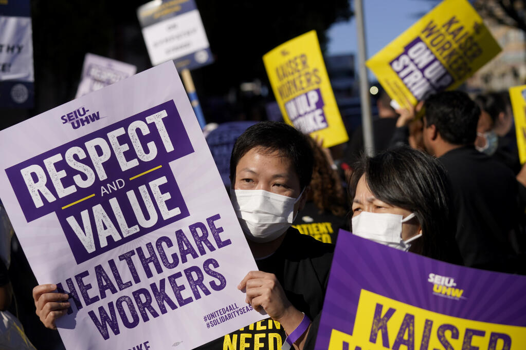 File - Medical workers and supporters carry signs and march as they protest outside of a Kaiser Permanente facility in San Francisco, Wednesday, Oct. 4, 2023. Thousands of workers who were asked to make sacrifices during the pandemic even as corporate profits soared are now asking for better pay and protections(AP Photo/Jeff Chiu, File)