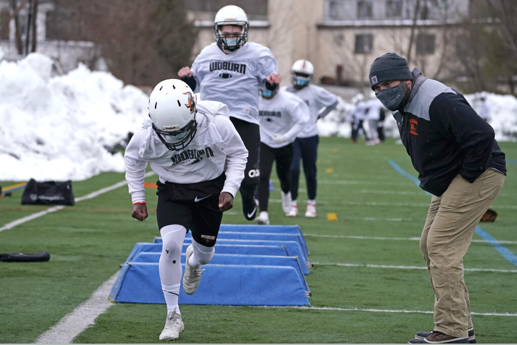 Associate head coach Vin McGrath watches his varsity players work out at a drill during the first day of football practice at Woburn High School on Feb. 22, 2021, in Woburn, Massachusetts.