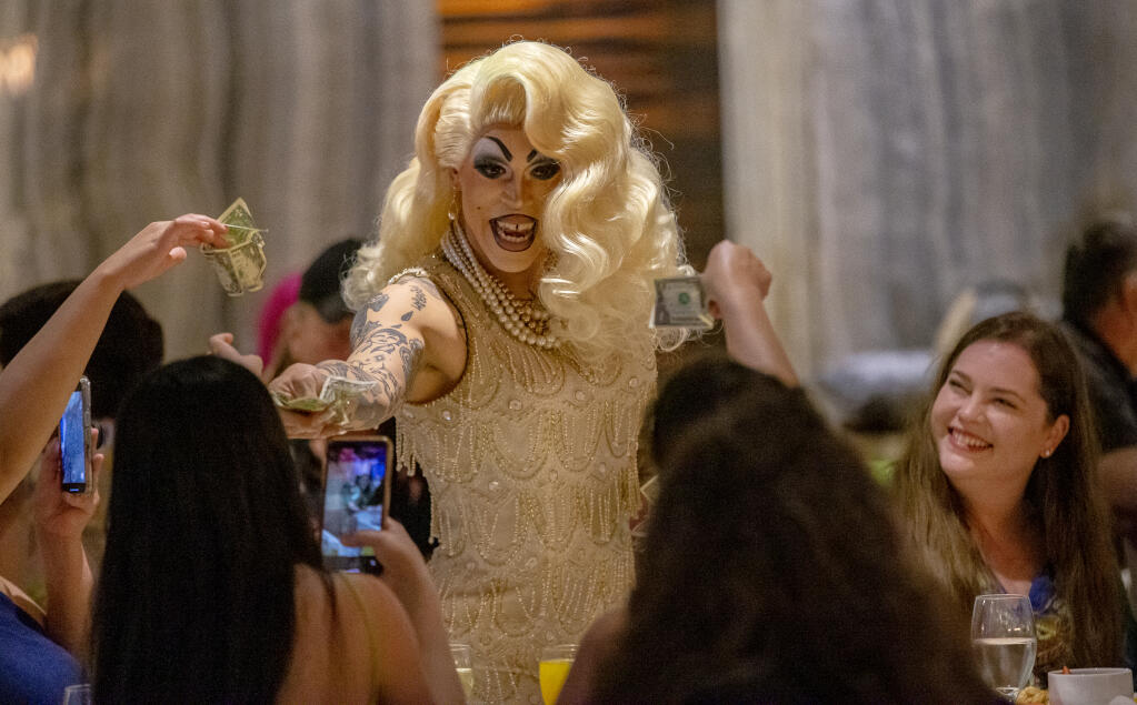 Drag performer Kochina Rude collects tips while singing and dancing during the annual pride drag brunch “Wigs and Waffles” at 630 Park Steakhouse inside the Graton Resort & Casino in Rohnert Park  June 4, 2023.  (Chad Surmick / The Press Democrat)