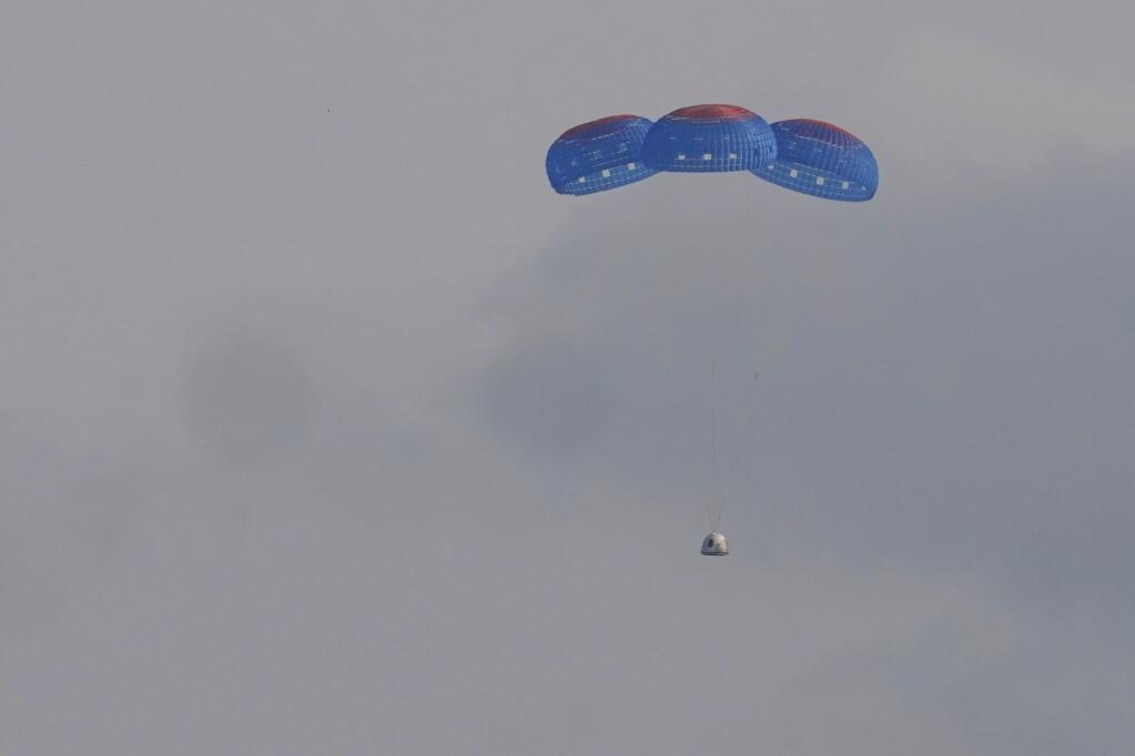 Blue Origin's New Shepard capsule parachutes safely down to the launch area with passengers Jeff Bezos, founder of Amazon and space tourism company Blue Origin, brother Mark Bezos, Oliver Daemen and Wally Funk, near Van Horn, Texas, Tuesday, July 20, 2021. (AP Photo/Tony Gutierrez)