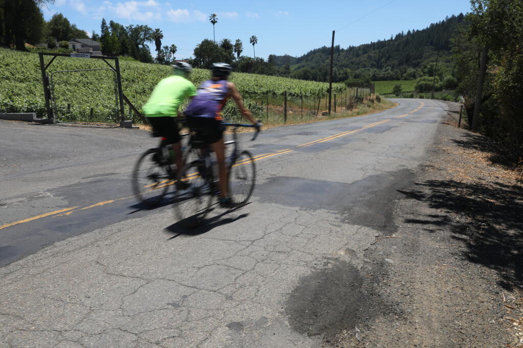 Cyclists ride along the cracked Wohler Road, north of River Road, west of Santa Rosa on Wednesday, May 26, 2021.  The section of road will be repaired through Sonoma County's Pavement Preservation Program.  (Christopher Chung/ The Press Democrat)