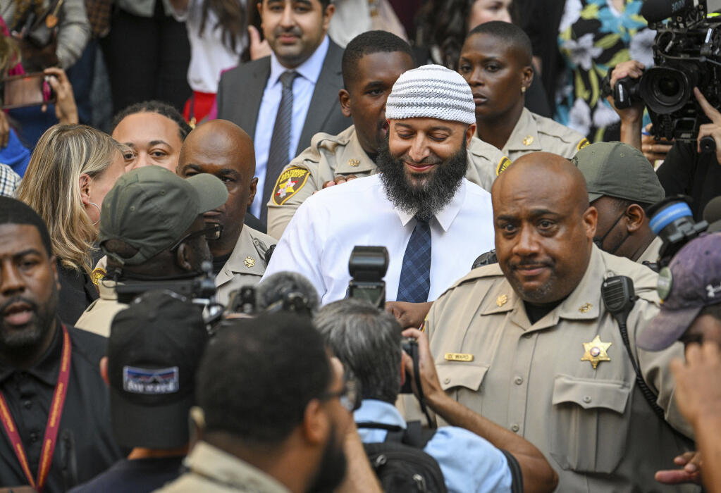 Adnan Syed, center, the man whose legal saga spawned the hit podcast "Serial," exits the Cummings Courthouse a free man after a Baltimore judge overturned his conviction for the 1999 murder of high school student Hae Min Lee, Monday, Sept, 19, 2022, in Baltimore. (Jerry Jackson/The Baltimore Sun via AP)