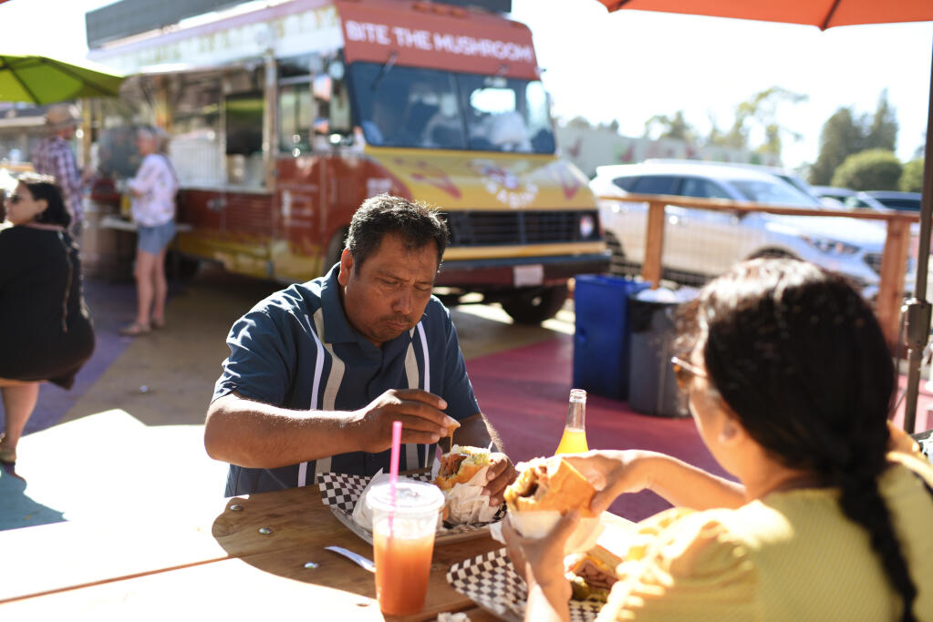 Manuel Ramirez, left, and Lucy Ochoa each enjoying a torta Cubana from the Gio y Los Magos Mexican Grill truck during the ribbon cutting celebration of the new Mitote Food Park on Sebastopol Road in the Roseland neighborhood of Santa Rosa, Calif. on Thursday, July 14, 2022.(Erik Castro / For The Press Democrat)