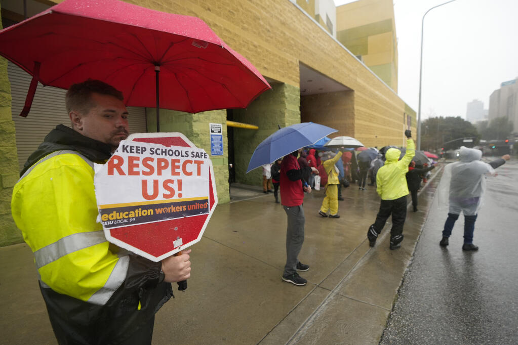 Los Angeles Unified School District, LAUSD teachers and Service Employees International Union 99 (SEIU) members strike under heavy rain outside the Edward R. Roybal Learning Center in Los Angeles Tuesday, March 21, 2023. Tens of thousands of workers in the LAUSD are walking off the job over stalled contract talks. (AP Photo/Damian Dovarganes)