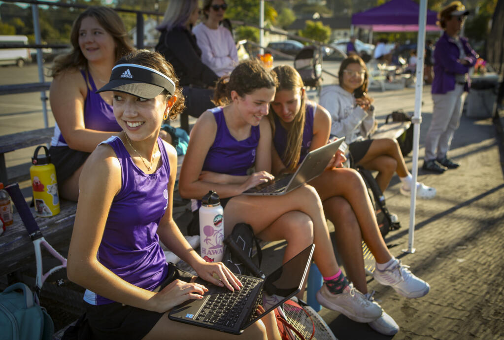 Maya Hoffman (far left), a junior at Petaluma High School, studies during a tennis match on Tuesday, Oct. 11, 2022. This year’s longer school days mean later start times for after school extracurriculars such as sports. (CRISSY PASCUAL/Argus-Courier Staff)