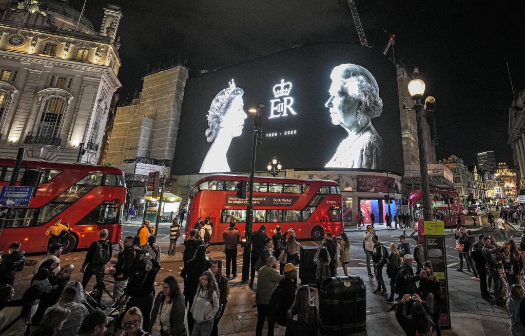 A big screen displays photos of Queen Elizabeth II at Piccadilly Circus in London, Friday, Sept. 9, 2022. Queen Elizabeth II, Britain's longest-reigning monarch and a rock of stability across much of a turbulent century, died Thursday Sept. 8, 2022, after 70 years on the throne. She was 96. (AP Photo/Martin Meissner)