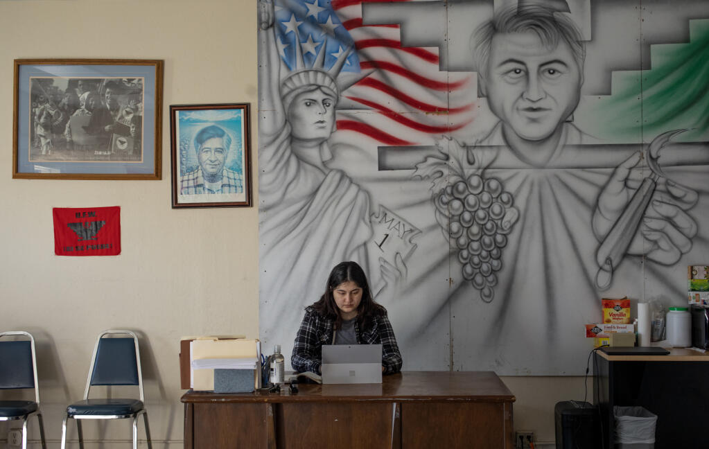 United Farm Workers Internal Organizing Coordinator Elizabeth Avila prepares  contracts to be distributed during field meeting with members and workers at the Santa Rosa office on Corby Avenue, Thursday, March 30, 2023. A mural of UFW co-founder Cesar Chavez covers the wall behind her work space. (Chad Surmick / The Press Democrat)