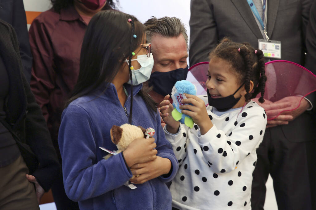 California Governor Gavin Newsom takes a photo with Luna Peña, 5, right, and another child, both who earlier had received their COVID-19 vaccines at the clinic at Unidos en Salud on Monday, November 22, 2021, in San Francisco. California now has one of the lowest coronavirus infection rates in the country. But Gov. Newsom is still warning of a potential surge in cases this winter. Newsom said other states have seen increases in cases because people are putting their guard down. (Lea Suzuki/San Francisco Chronicle via AP)