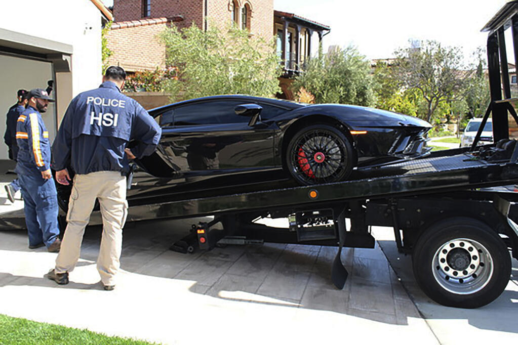 This photo provided by U.S. Immigration and Customs Enforcement shows special agents with HSI Los Angeles’s El Camino Real Financial Crimes Task Force seize a Ferrari from an Orange County businessman on Friday, April 7, 2021 in Irvine, Calif. Mustafa Qadiri, 38, of Irvine, was named in a federal grand jury indictment and has pleaded not guilty to charges he obtained $5 million in federal coronavirus-relief loans for phony businesses and then used the money for lavish vacations and to buy a Ferrari, Bentley and Lamborghini, prosecutors said Monday. (U.S. Immigration and Customs Enforcement via AP)