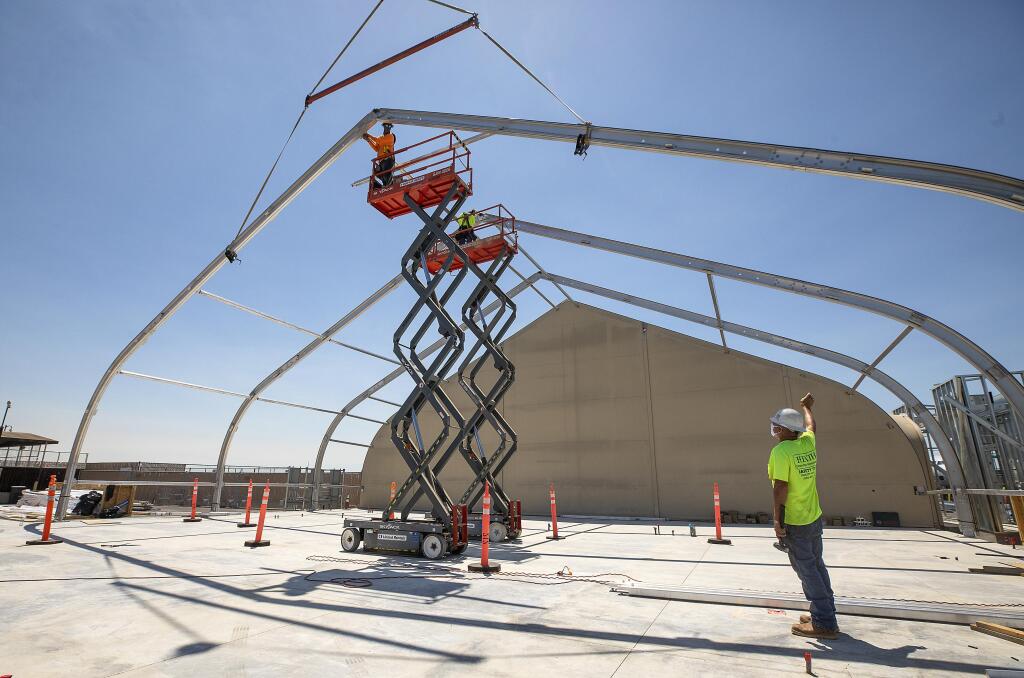 Crews raise the steel “ribs” of a passenger tent expansion to house the security checkpoint at the Charles M. Schulz-Sonoma County Airport, on Wednesday, July 15, 2020.  (John Burgess/The Press Democrat)