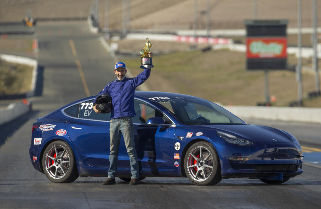 Craig Merrilees, pioneer and innovator, won a world championship in drag racing at the National Hot Rod Association Racing Summit in Las Vegas. He drove his modified blue Tesla Model 3 Performance in the brand new Street Legal EV class to a time of 11.45 seconds. He shows off his trophy at the drag line of Sonoma Raceway Wednesday Nov. 16, 2022. (Chad Surmick / Press Democrat)