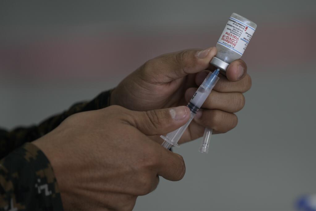 A health worker prepares a booster dose of the Moderna vaccine for COVID-19 at the Air Force Base in Guatemala City, Monday, Jan. 10, 2022. (AP Photo/Moises Castillo)