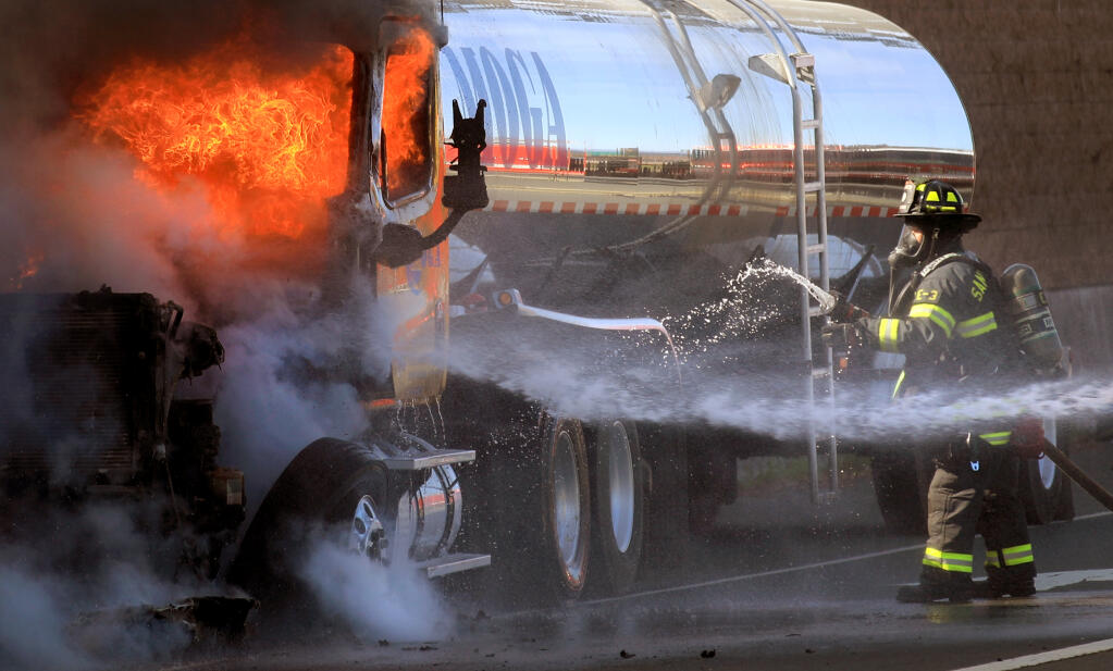 Santa Rosa firefighters extinguish fire overtaking the cab of a tanker truck on the off-ramp of south Highway 101 at College Avenue in Santa Rosa on Tuesday, March 23, 2021. (Kent Porter / The Press Democrat) 2021