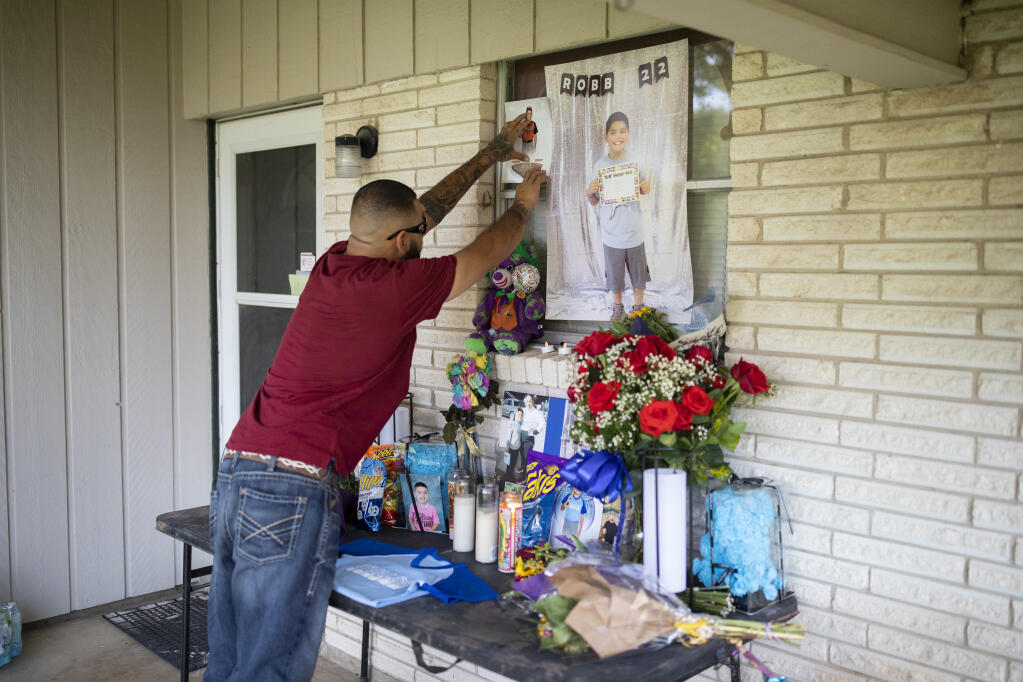 Jose Manuel Flores Sr. rearranges a makeshift memorial for his son, Jose Flores, one of 19 children killed by a gunman at Robb Elementary School, at his home in Uvalde, Texas on May 28, 2022. In Uvalde where many children were killed, one family grieves the death of a small boy and holds his sister close. (Ivan Pierre Aguirre/The New York Times)