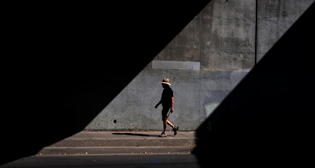 A pedestrian takes a stroll in the late summer sun, Thursday, Sept. 15, 2022 along Olive Ave., at the Highway 12 over crossing in Santa Rosa. (Kent Porter / The Press Democrat) 2022