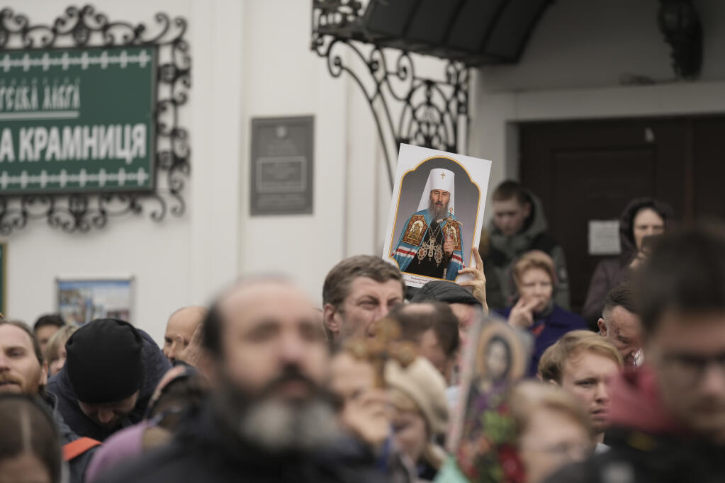 Supporters of Ukrainian Orthodox Church hold a portrait of Metropolitan Onufriy as monks have resisted a government order to leave the Kyiv Pechersk Lavra monastery complex in Kyiv, Ukraine, Saturday, April 1, 2023. In a bitter dispute over a famed Orthodox monastery, Ukraine's top security agency notified a leading priest on Saturday that he was suspected of justifying Russia's aggression, a criminal offense, Metropolitan Pavel, the abbot of the Kyiv-Pechersk Lavra monastery, Ukraine's most revered Orthodox site, has resisted the authorities' order to vacate the complex. Earlier in the week, he cursed Ukrainian President Volodymyr Zelenskyy, threatening him with damnation. (AP Photo/Roman Hrytsyna)